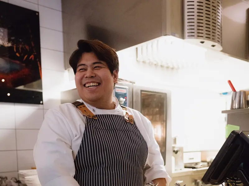 Kokk anretter en rett med presisjon på Yggdrasila-kjøkkenet.